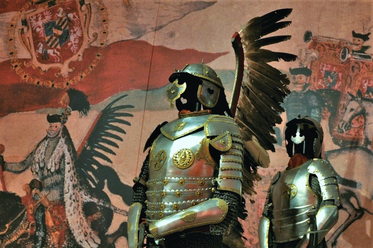  A photo of a Polish hussar armor found in Mikułowice. The armor is made of steel and has a bevor, a winged helmet, and a breastplate with a skirt of lames. It also has a pair of wings made of feathers attached to the back of the breastplate.