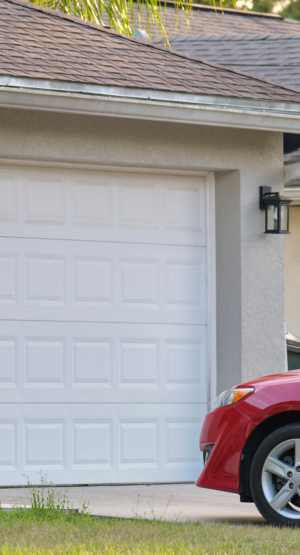 Vehicle parked in front of wide garage double door on paved driveway of typical contemporary american home